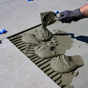 a person using grout to stick down a tile
