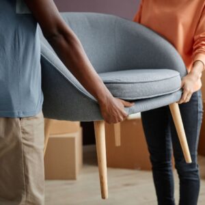 two people carrying a chair